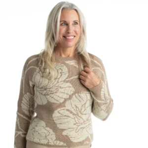 A woman in a tan sweater with white flowers.