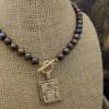 A necklace with a gold buddha charm and brown beads.
