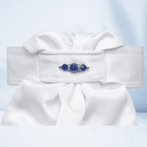A white bow with blue beads on it.